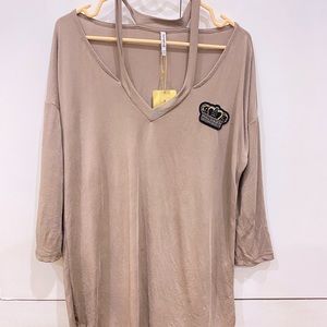 A toupe coloured top with a tag .